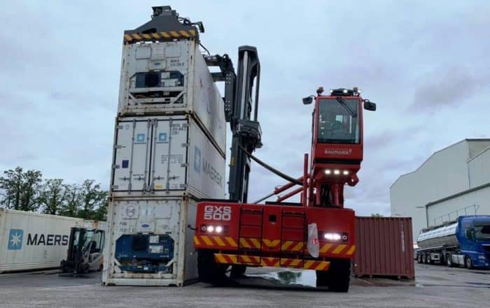 Large side loader next to stacked containers
